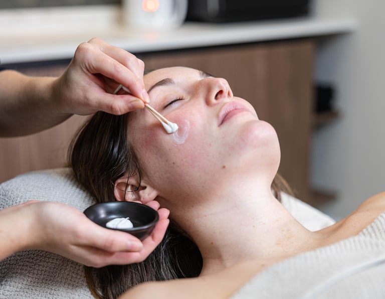 a woman getting her face covered in a mask at a salon