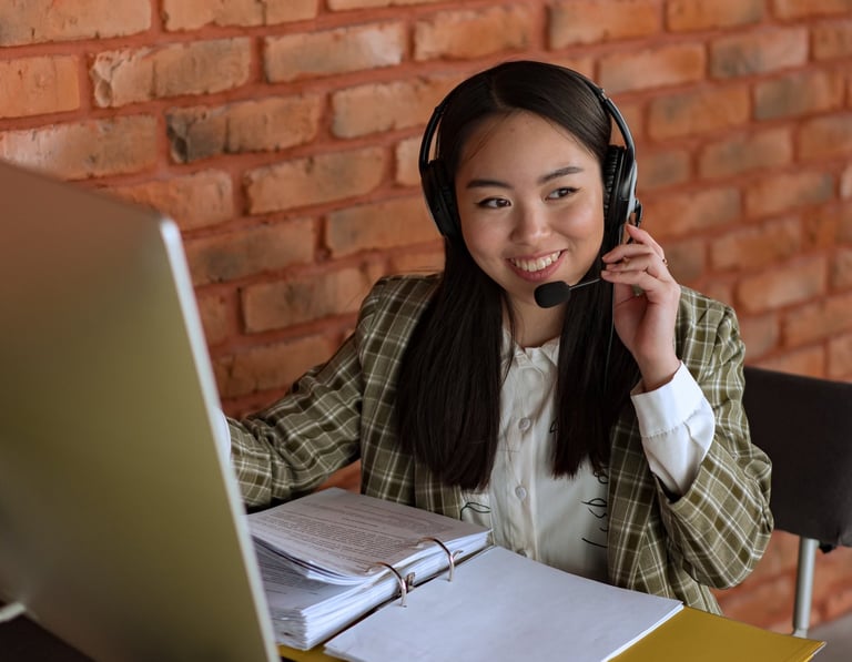 a woman in a plaid shirt and headphones on a laptop