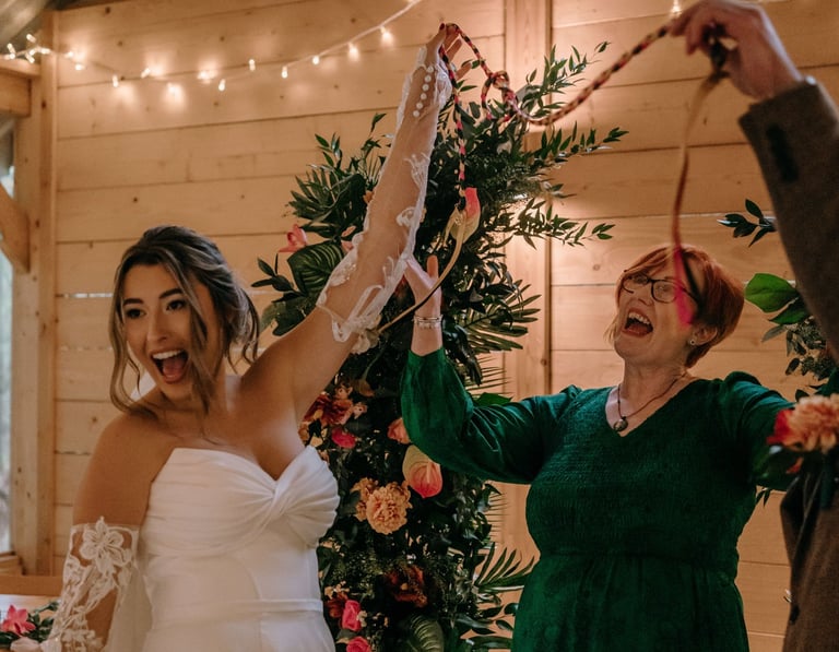 Wedding couple and celebrant smiling and laughing after a handfasting ceremony