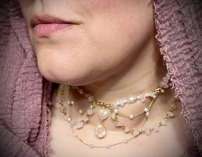 a woman in pink hijab wearing a delicate multi-chain necklace with rose quartz and pearl beads