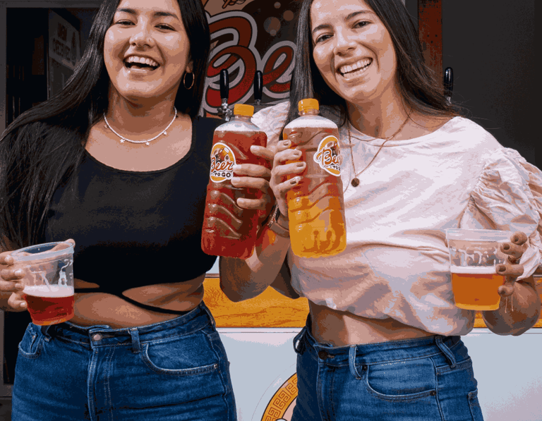 2 mujeres sonriendo sosteniendo vasos y botellas de cerveza artesanal