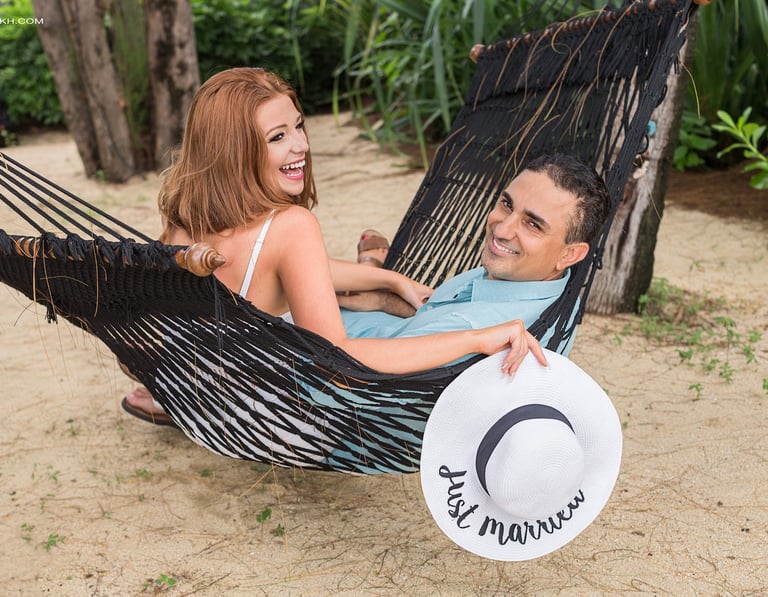 A joyful newlywed couple lounging in a black hammock on a sandy tropical beach in Koh Samui