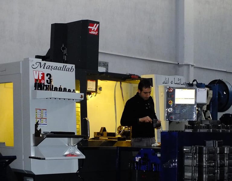 a man in a black shirt is standing in a machine shop