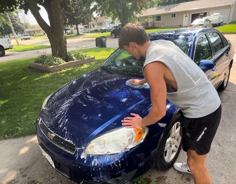 Golden mobile detailing team giving a blue sedan an exterior wash