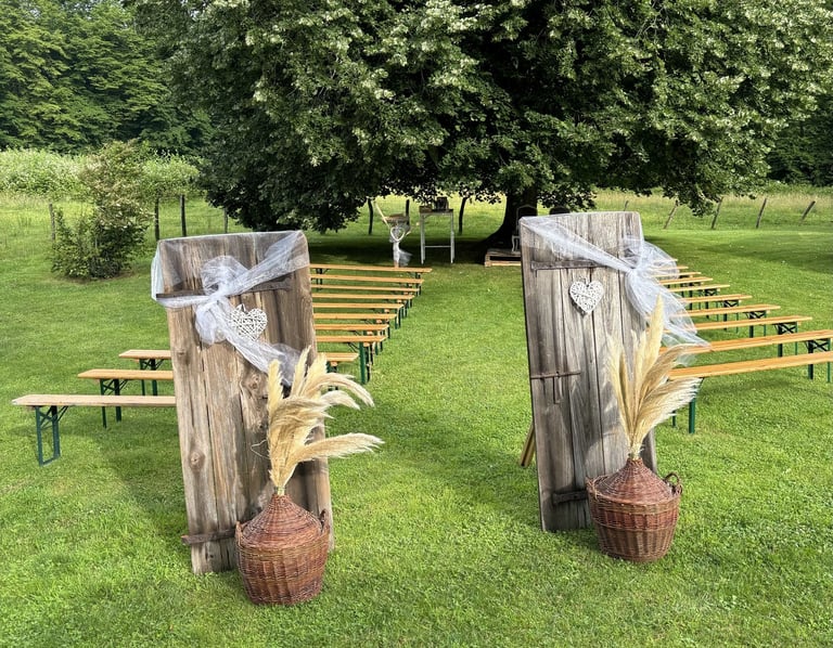 Cérémonie laïque dans un pré sous un chêne, bancs, porte et décoration champêtre pour cérémonie symbolique