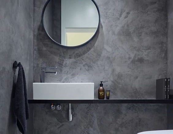 Badkamer afgewerkt met Mortex pleister, met een ronde wastafel en spiegel.