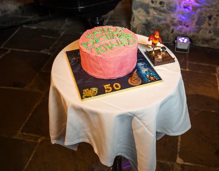Pink birthday cake on display table in event hall, photographed by Fred Art Studio.