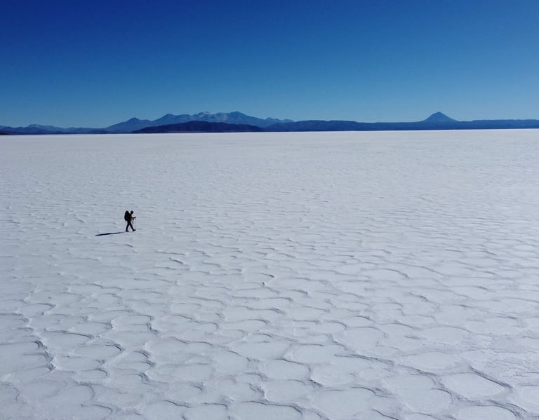Un randonneur solitaire marche à travers l’immensité blanche du salar d’Uyuni en Bolivie