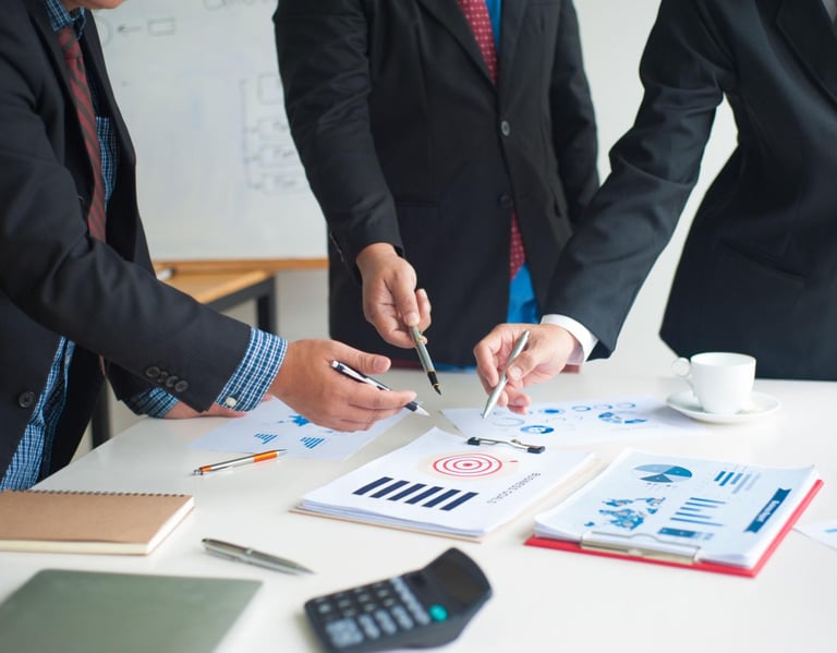 Business team in suits pointing at data charts and target goals during a corporate strategy meeting.