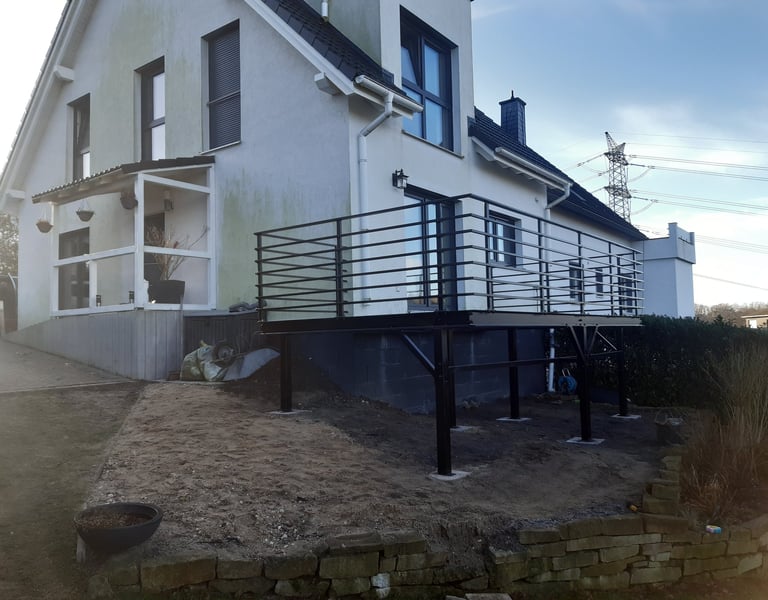 Modern black metal balcony railing installed on a raised outdoor metal deck.
