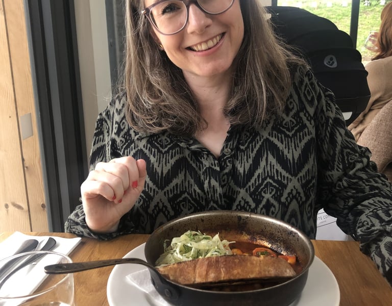 a woman with glasses smiles. She is out for lunch.