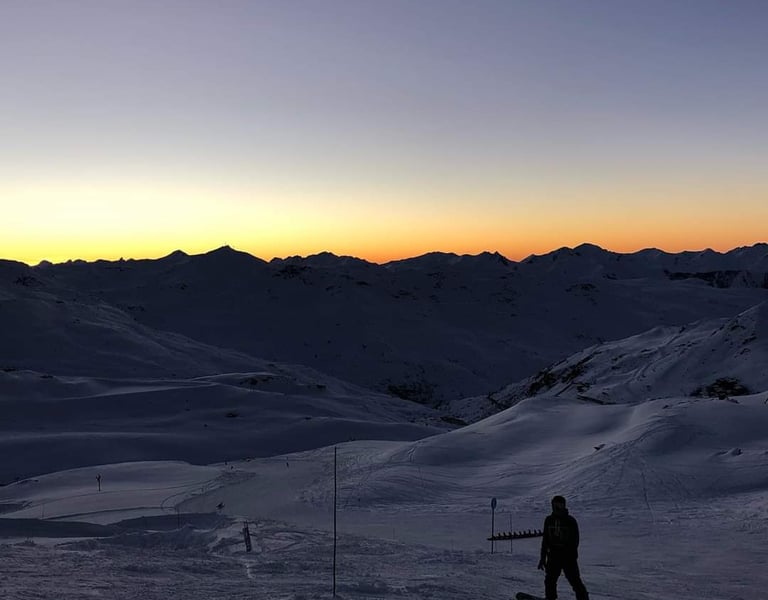 Skier overlooking snowy alpine slopes at sunset in Val Thorens with direct access to the 3 Valleys ski area