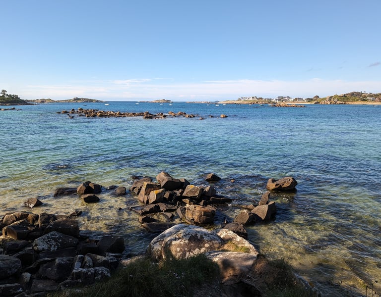 bord de mer, Eau cristalline, rochers et îlots sous un ciel bleu, offrant un paysage côtier apaisant