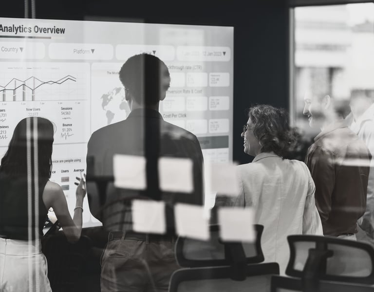 a group of people standing in front of a white board looking at slide titled Data Analytics Overview