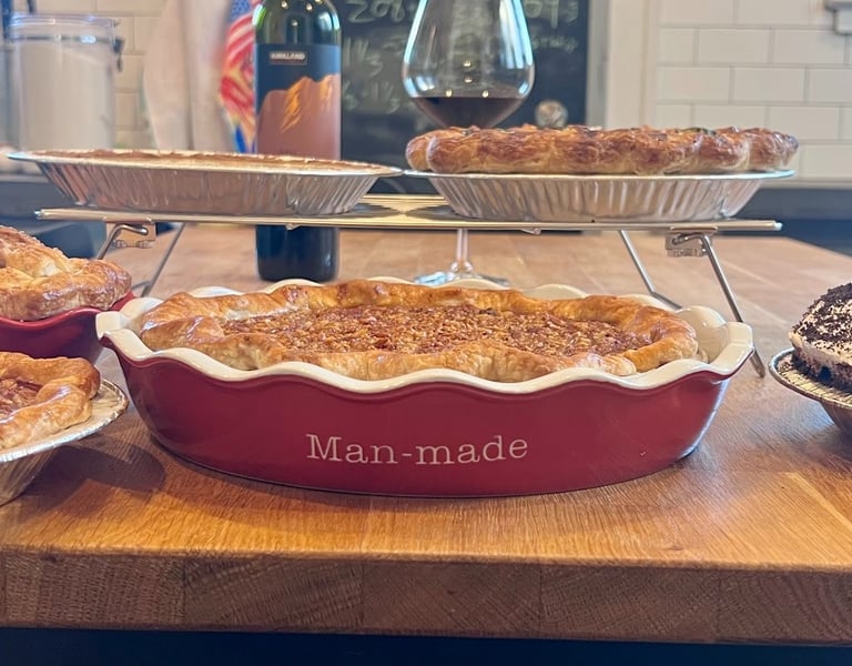 Selection of homemade holiday pies and wine on a butcher block kitchen island for Thanksgiving.