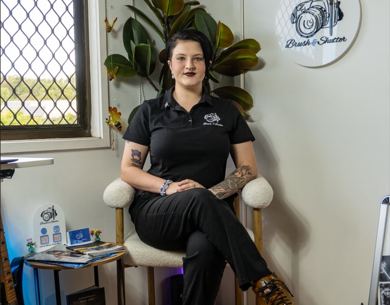 Professional female photographer sitting in her studio at Brush and Shutter with camera gear and art decor.