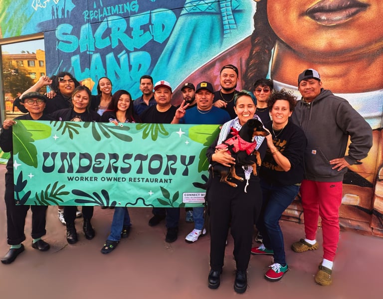 Understory workers standing in front of a mural of a man holding a banner