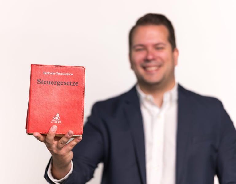 Steuerberater Niklas Schüller hält das Steuergesetzbuch in der Hand