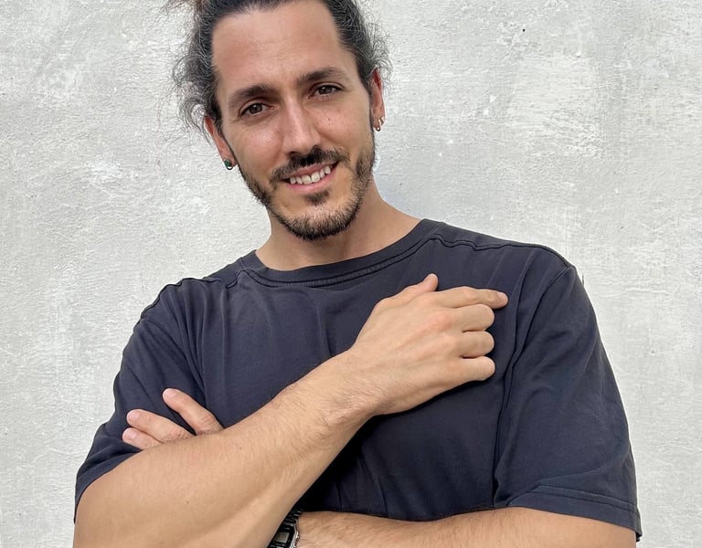 Borja Llegó posando de brazos cruzados frente a una pared gris, creador de contenido de viajes y gas