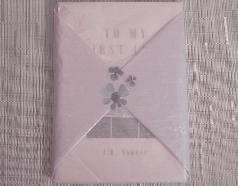 J.R. Sonder's book To My First Love (TMFL) wrapped in purple tissue wrap with a purple flower.
