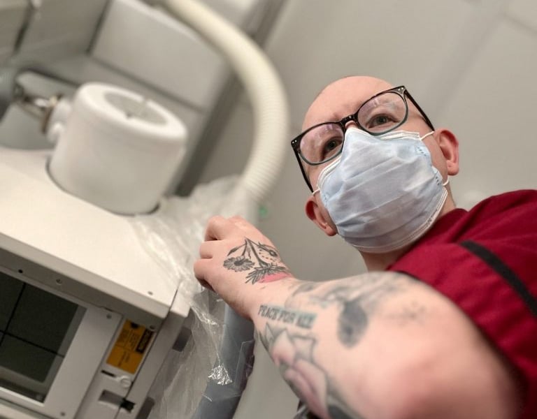 Ben, pictured here in radiographer uniform, operating medical X-ray equipment in a hospital setting.