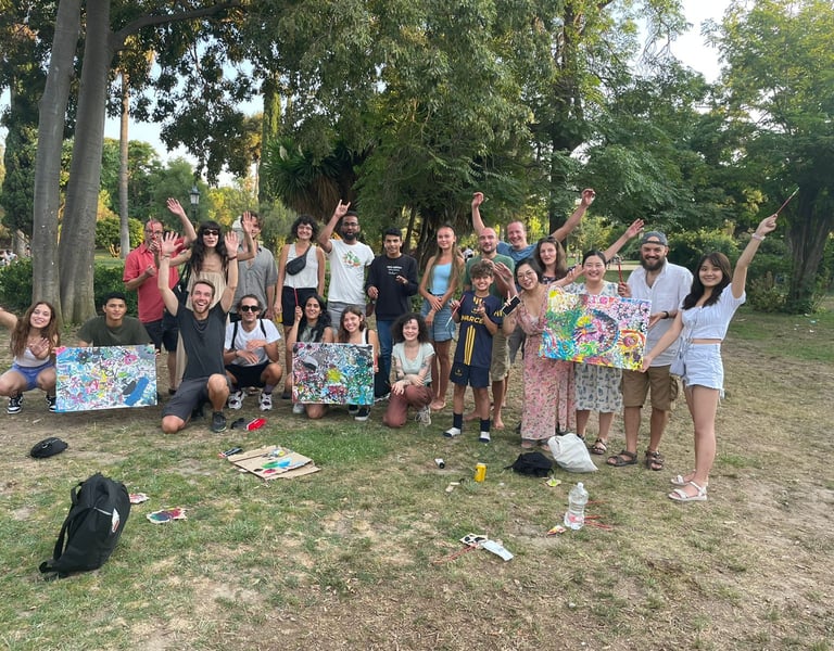 Des amis souriants tiennent des tableaux abstraits lors d’un événement artistique dans un parc