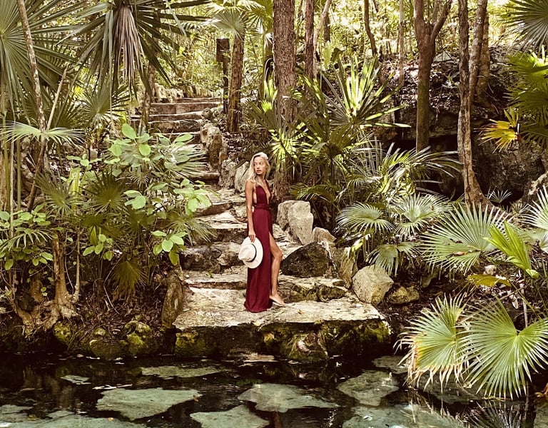 mujer en un cenote usando vestido rojo boho y sombrero en la mano. jungla selva. Tulum