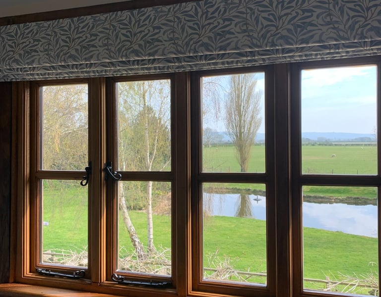 A roman blind in a leafy fabric designed to work with the view of open fields