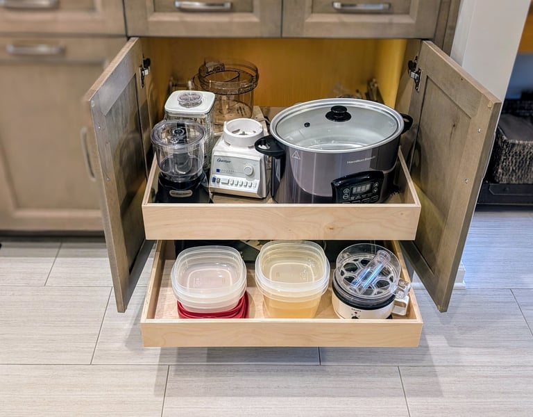 A kitchen cabinet with custom slide out shelves that are fully loaded with kitchen items.