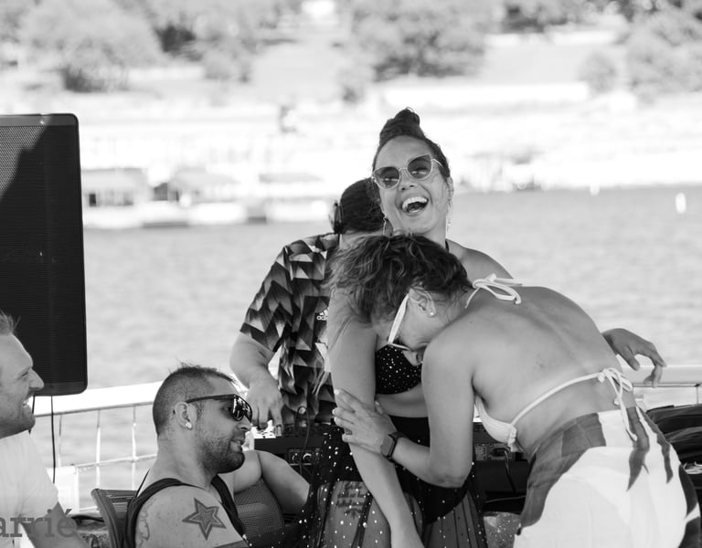 to women laughing raciously on a boat party sourrounded by people