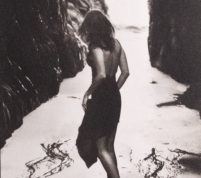 SIlver and Platinum photo of a woman in a black dress standing on a beach