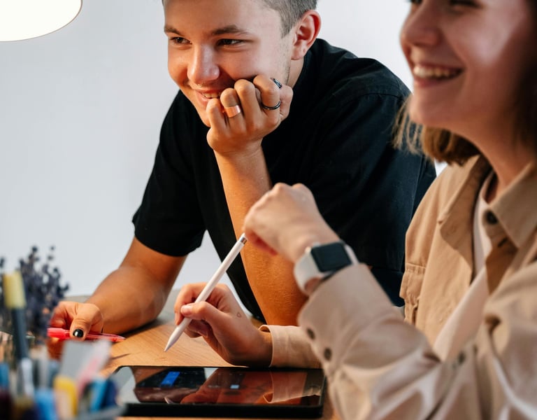 A Young Man Beside a Woman Sitting at Table Holding a Stylus