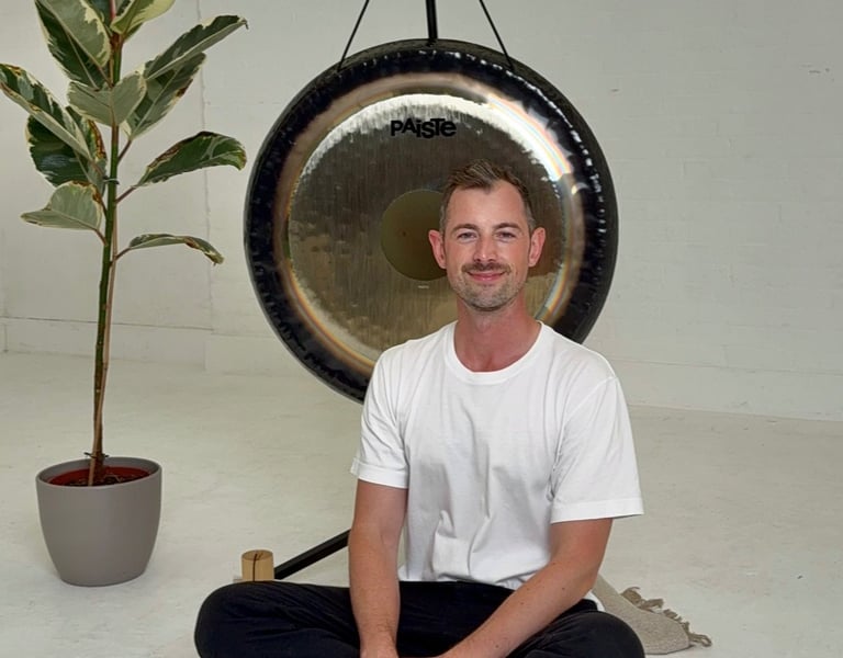 a man sitting in front of a gong in a calming space