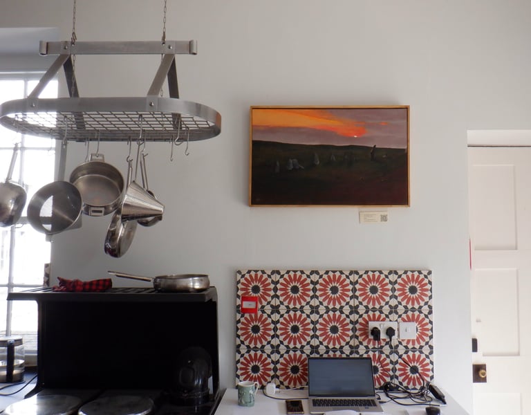 Home office setup in a kitchen with a laptop on a desk against a colorful patterned backsplash.