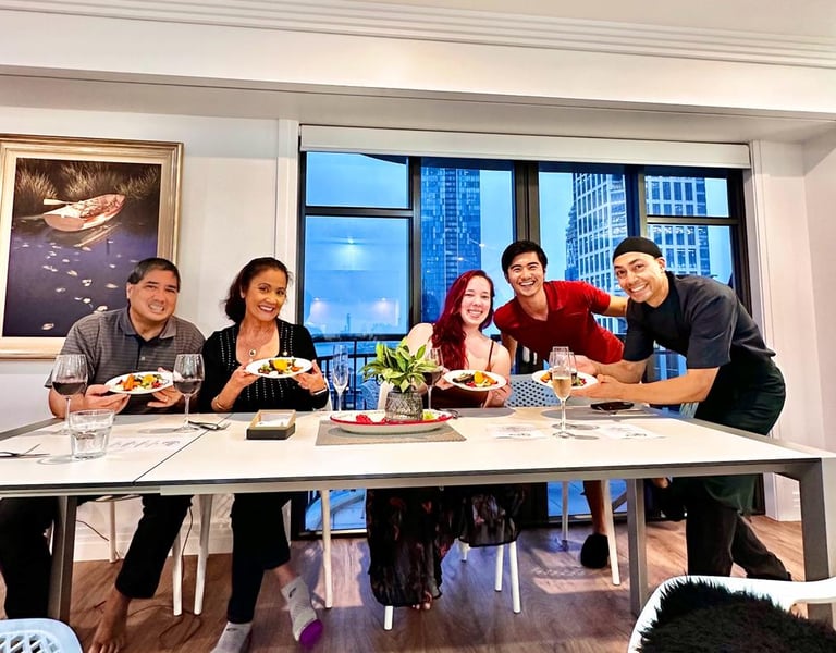Smiling group of friends enjoying a luxury private chef dining experience at home with city views.