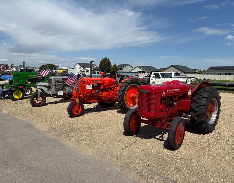 a row of tractors parked in a gravel lot