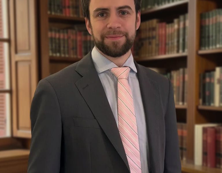Lawyer in a suit and pink tie posing in a traditional library with law books.