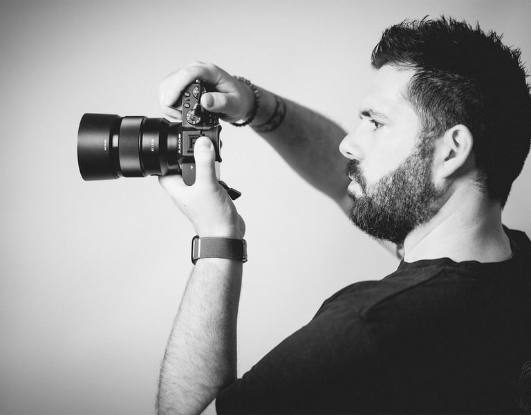 Portrait en noir et blanc de Cyril Steau, photographe à Paris, en pleine prise de vue avec un appareil photo professionnel.