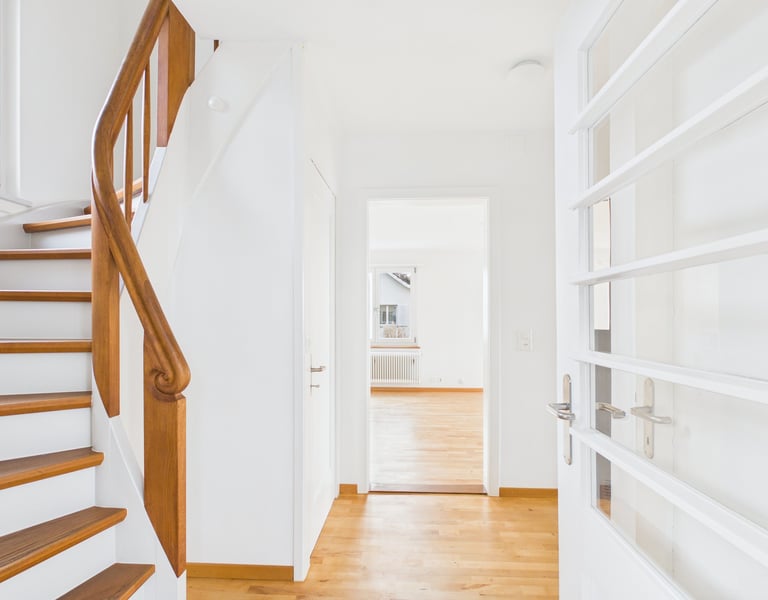 Heller, moderner Flur mit Eichenparkett und einer Holztreppe, die nach oben führt.