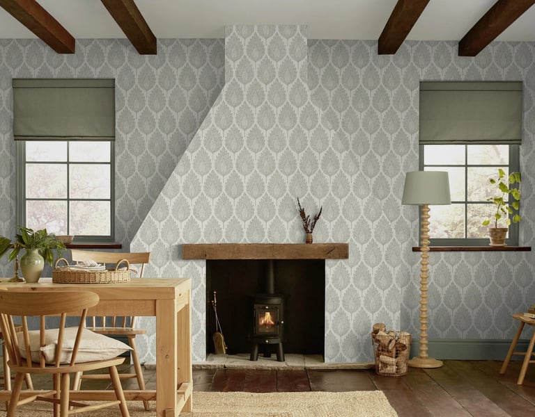 Rustic living room featuring grey leaf patterned wallpaper, a wood burning stove, and exposed ceiling beams.