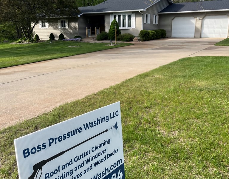 Boss Pressure Washing LLC yard sign in front of a freshly cleaned driveway and home.
