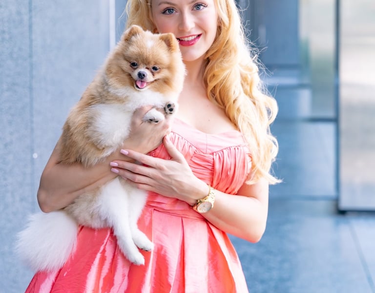 Founder of Liebe Chronicles holding Liebe, a dapper toy Pomeranian, in an urban setting.