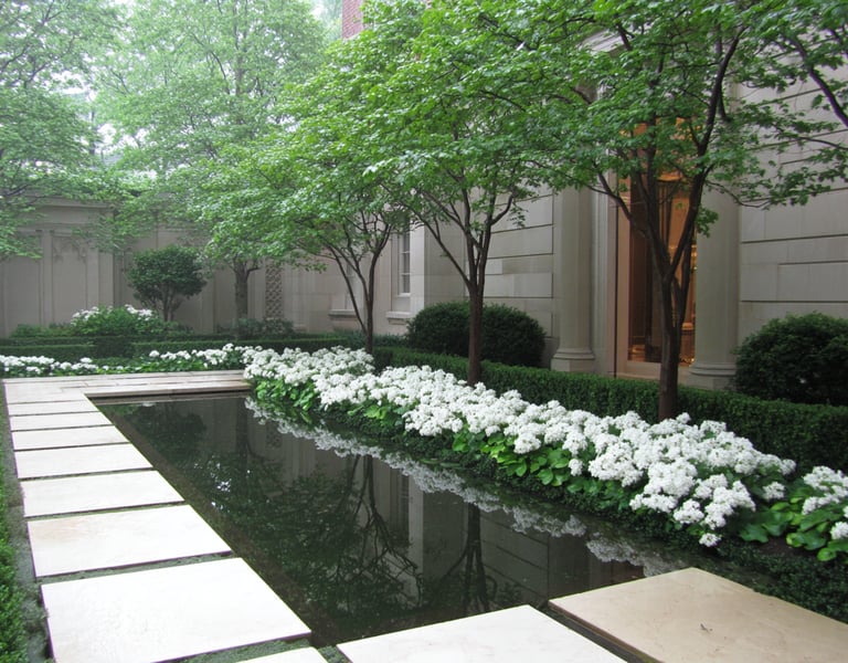 Elegant garden courtyard with white hydrangeas bordering a reflecting pool and stone pavers.