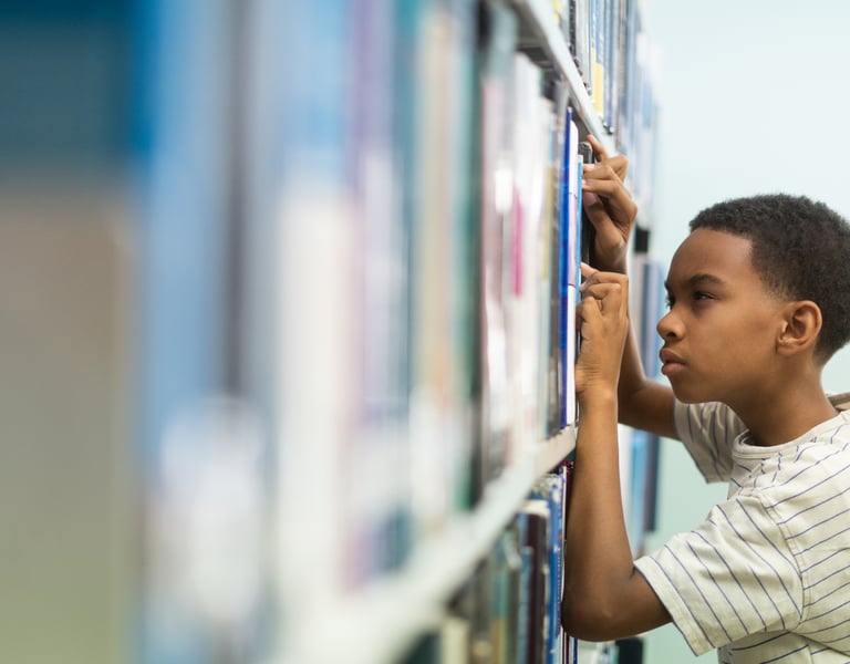 Child with myopia squinting while trying to find a book in the library