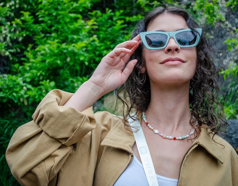 Woman outside looking up and touching her eco-conscious sunglasses