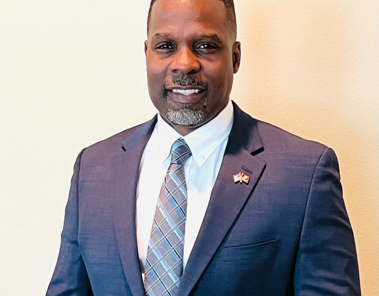 Dr. Marlon Ware professional headshot in blue suit with blue striped tie