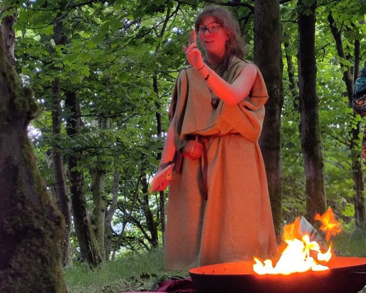 a woman in a robe is standing in front of a fire pit
