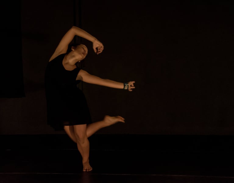 a woman in a black dress is dancing on stage