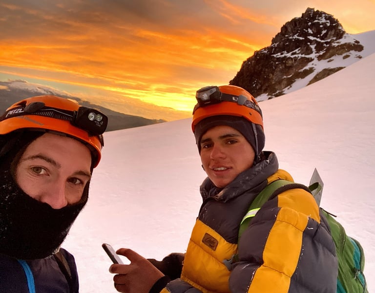 Montañistas ascendiendo en fila por la arista de roca y nieve con neblina andina.