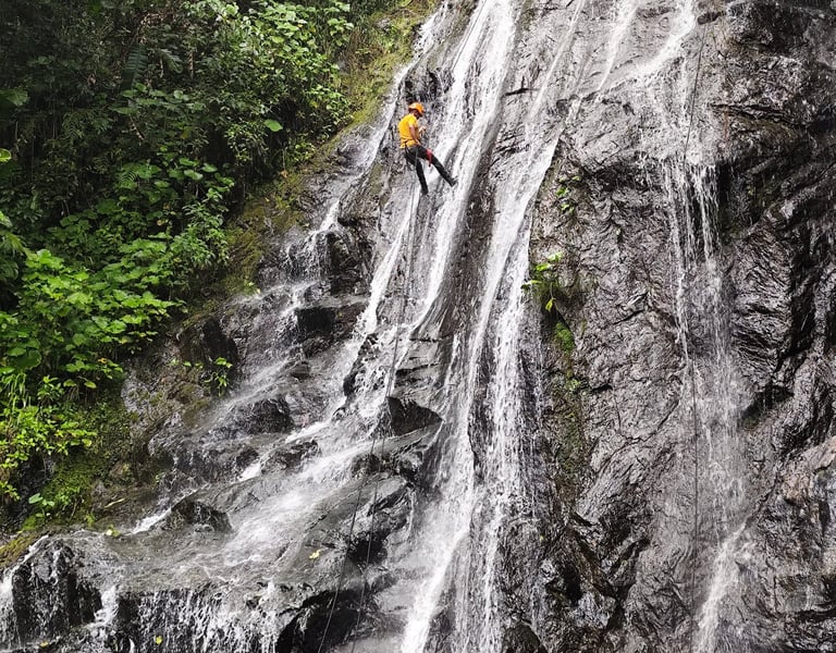 Persona descendiendo en rápel por una cascada.